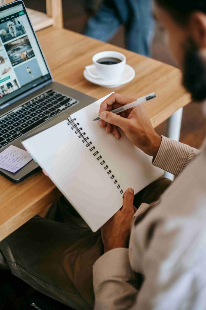 Person planning work uses notebook and computer